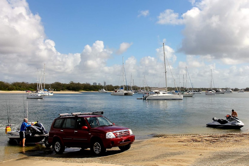 A red car backing a jet ski into the water on a sunny day at the Broadwater.