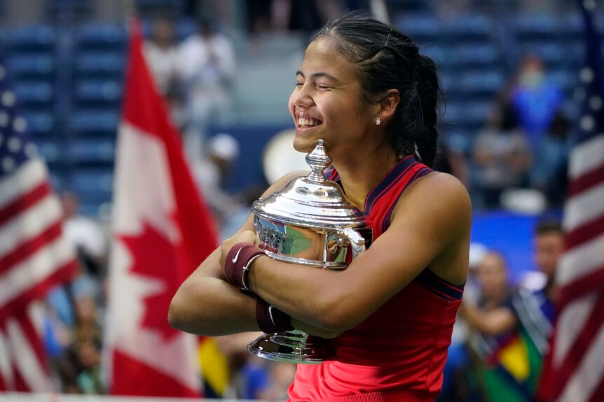 Emma Raducanu hugs the silver US Open trophy to her chest and smiles with her eyes closed