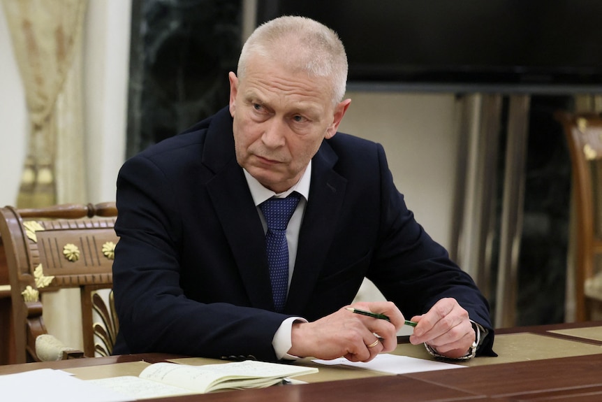 A man in suit attends a meeting. 