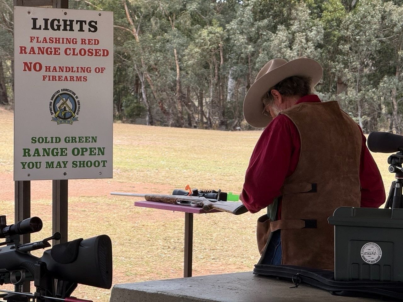 Un hombre mira un rifle en un campo de tiro.