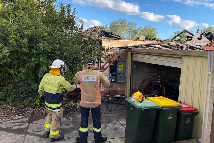 Metropolitan Fire Service (MFS) officers survey the house and shed from the driveway