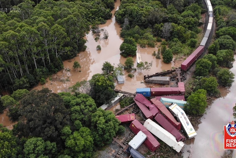 Aerial view of derailed goods train surrounded by flooded paddocks with carriages in water and on their side