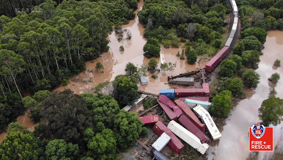 Aerial view of derailed goods train surrounded by flooded paddocks with carriages in water and on their side