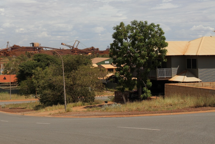 A street corner with a sign reading Kingsmill Street in the foreground, houses, and iron ore industry in the background
