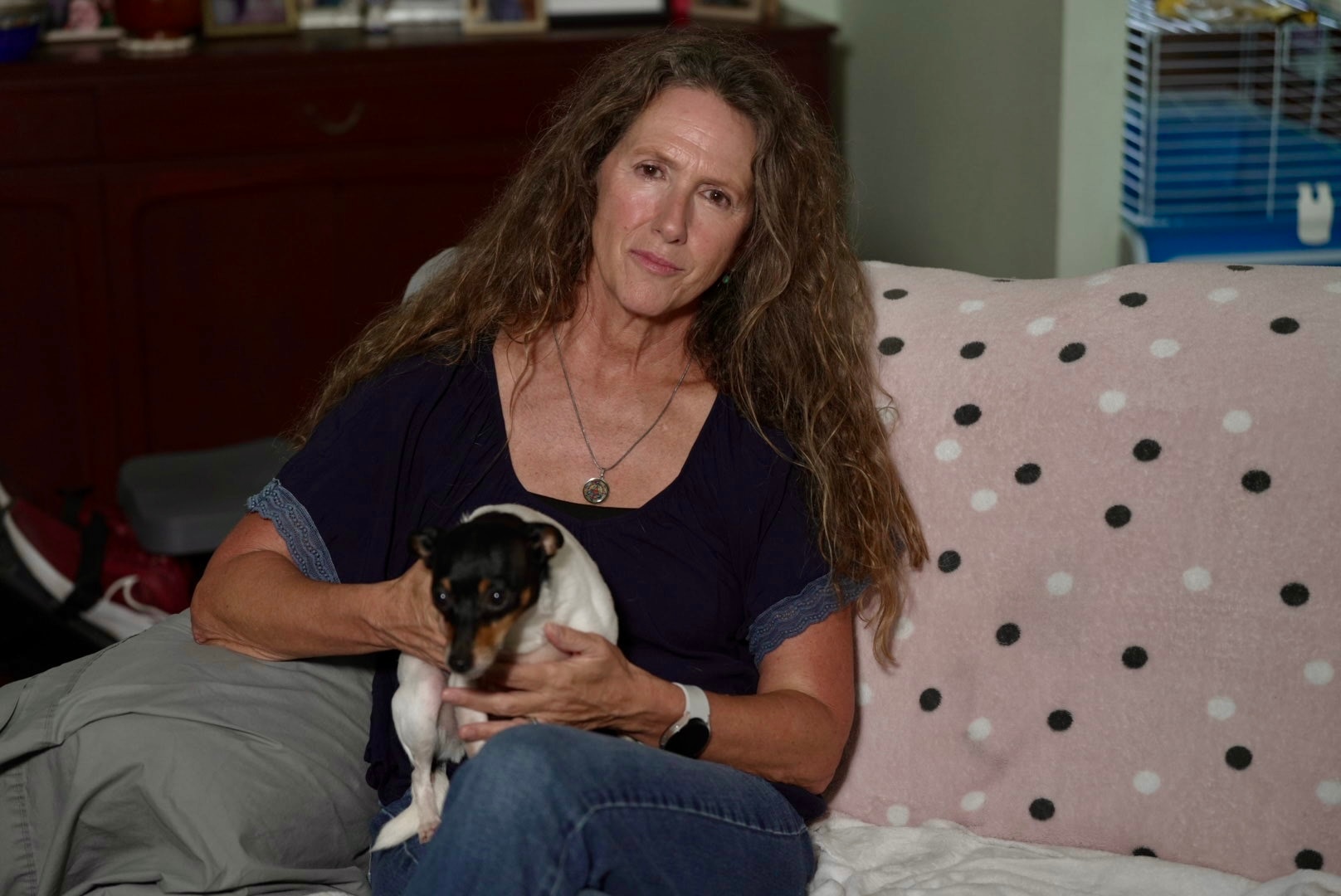 Geraldine Kirkcaldie está sentada em um sofá com um cachorro no colo.