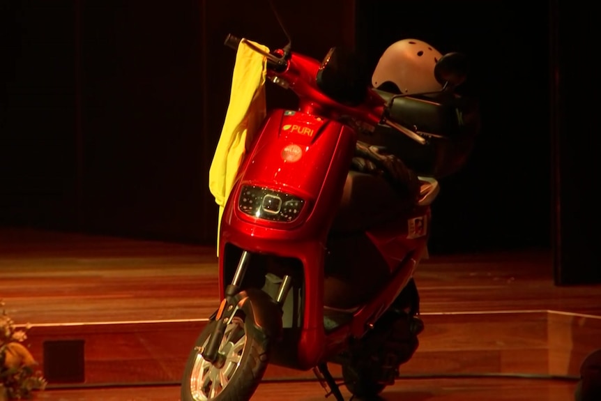 A red scooter on a stage.