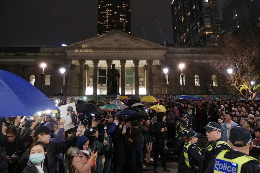 Hundreds of protesters stand out the front of state library of Victoria at night