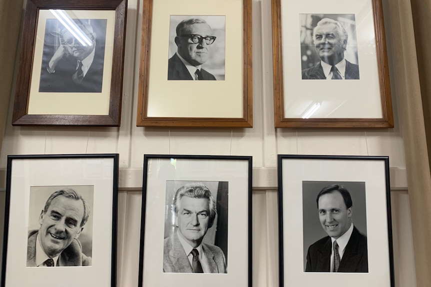 Eine Wand mit Fotos von lächelnden alten Männern