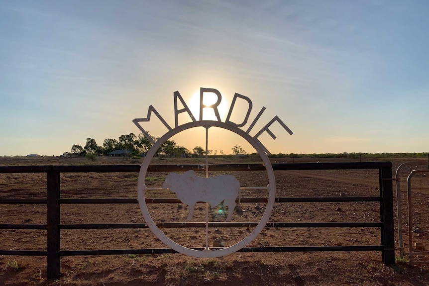 The sun sets in a clear blue sky behind the Mardie Station homestead sign
