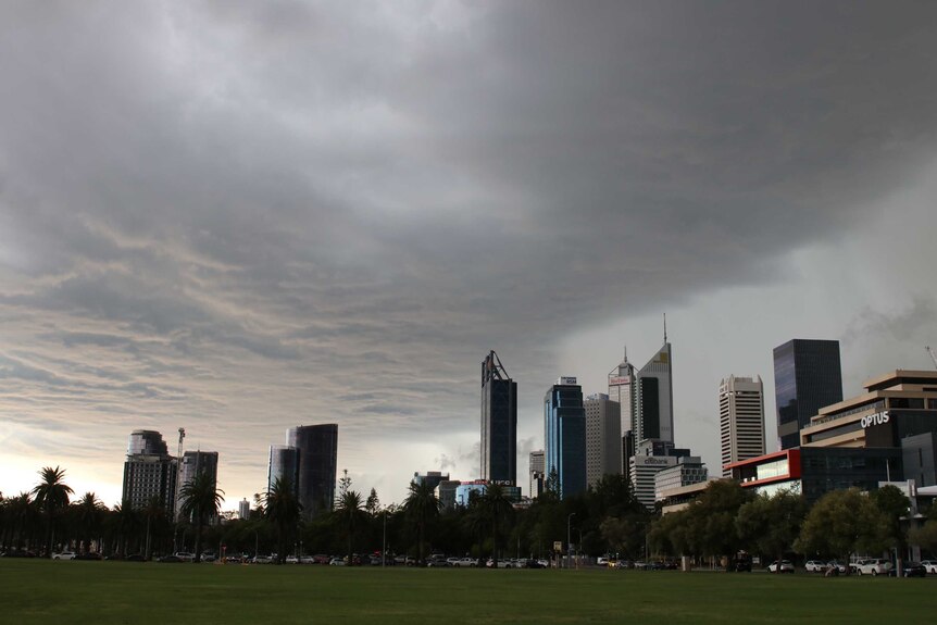 Heavy storm clouds over the Perth CBD and Langley Park with rain starting to fall on tall city buildings.
