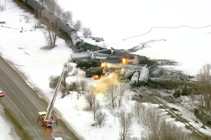 A ladder fire truck tries to extinguish a train fire.