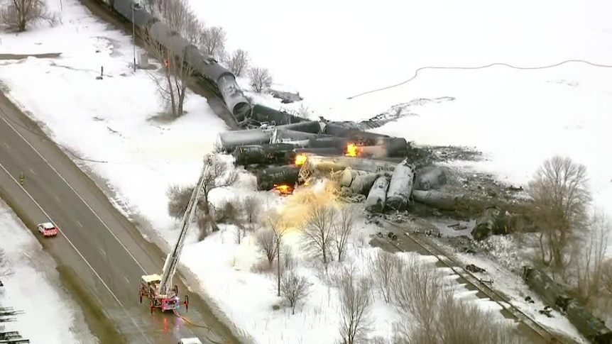 A ladder fire truck tries to extinguish a train fire.