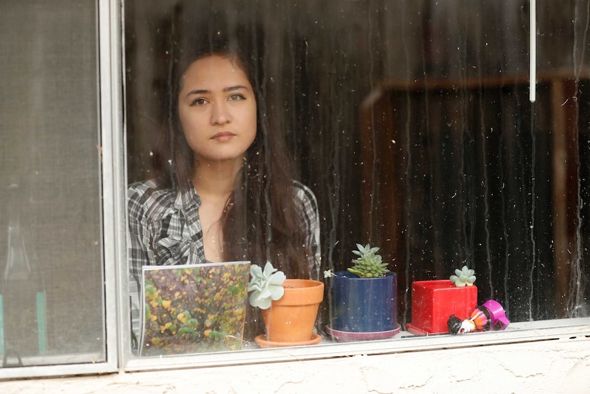 Anna looking through rainy window.