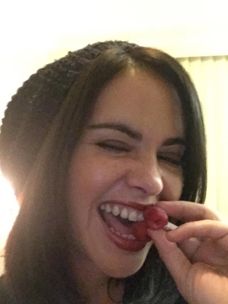 Girl in hat laughing and eating raspberries