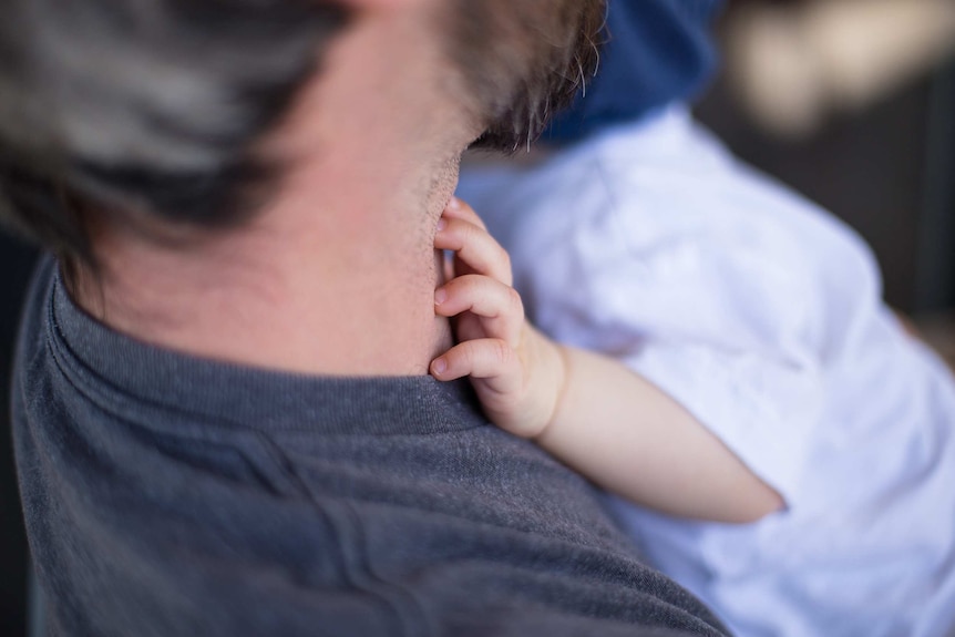 A photo of an unidentifiable man holding a young child.