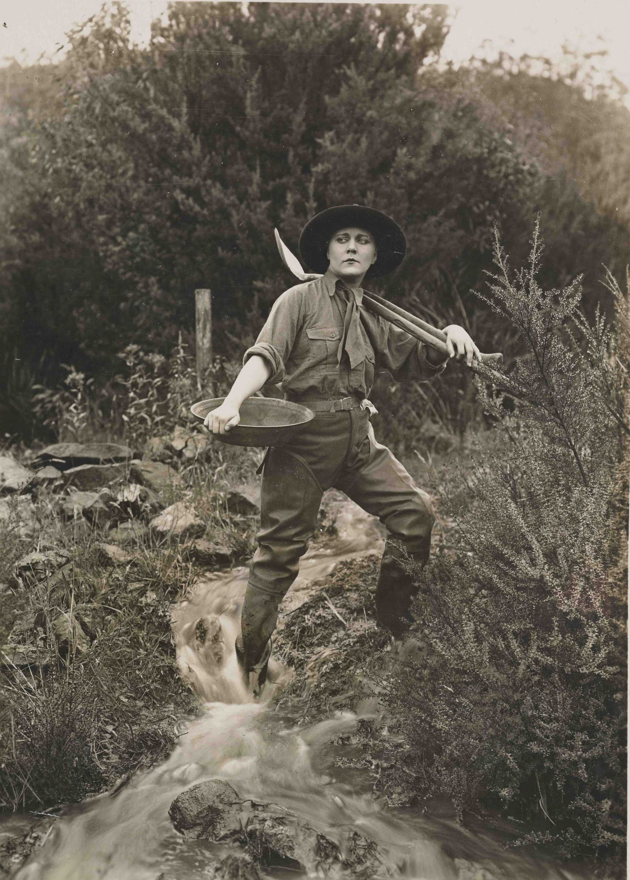 Black and white photo a woman in jodhpurs holding a pan and shovel