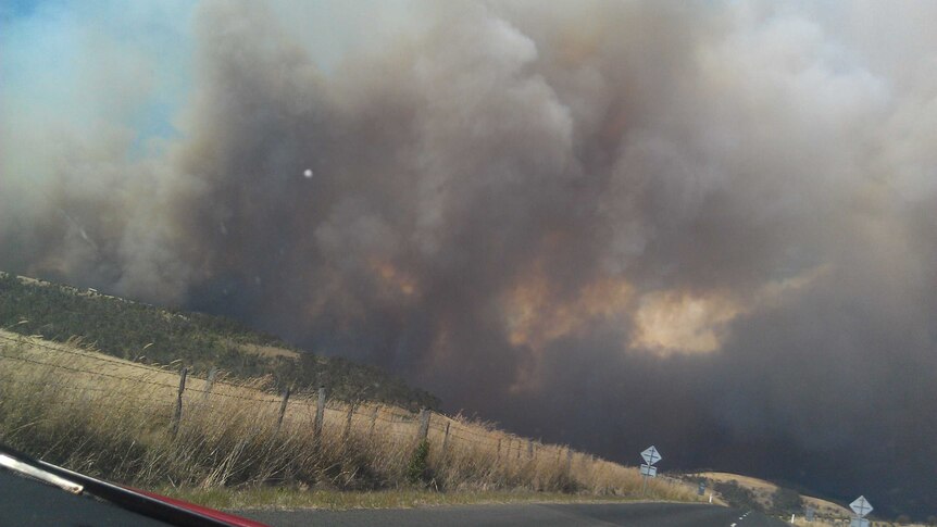 Photograph of smoke billowing from a bushfire, seen from a road out of Primrose Sands.