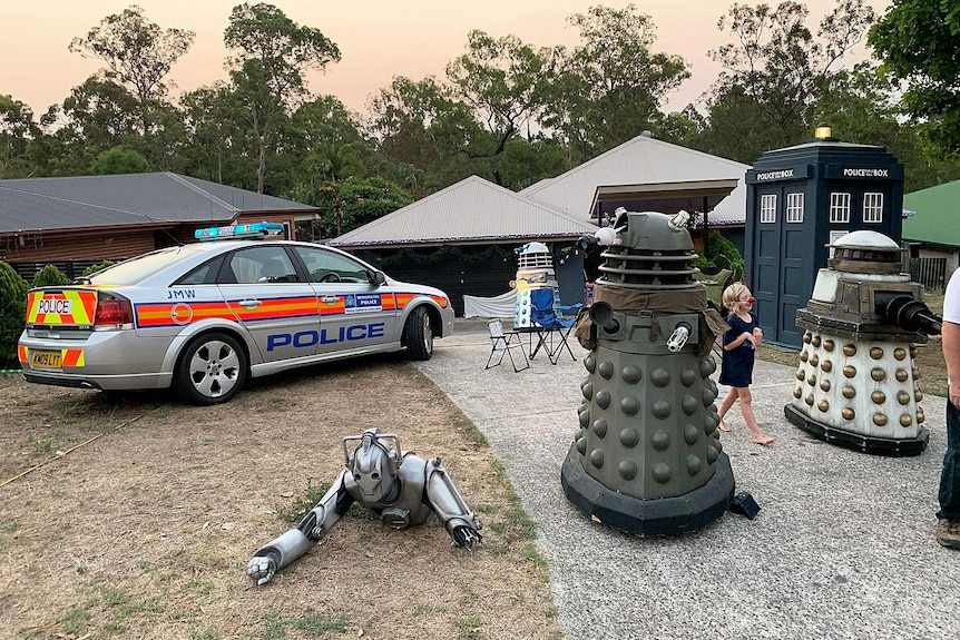 Doctor Who props three daleks, a TARDIS and a British police car displayed in Ipswich front yard.