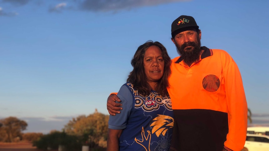 A man and a woman standing together at sunset.