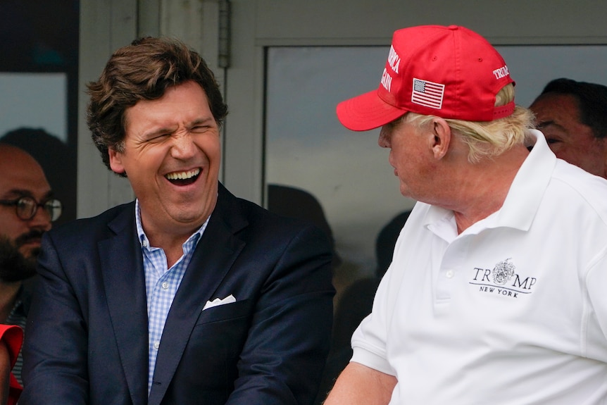 Tucker Carlson laughs as he talks to Donald Trump