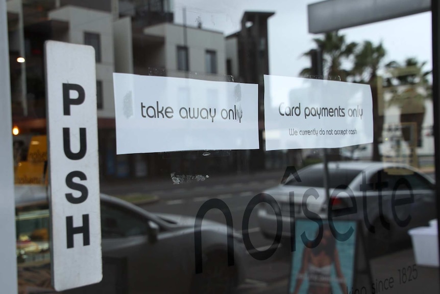 A sign on a cafe glass door says takeaway only and card payments only.