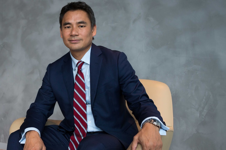 Westpac executive Yung Ngo sits on a chair with a grey background.