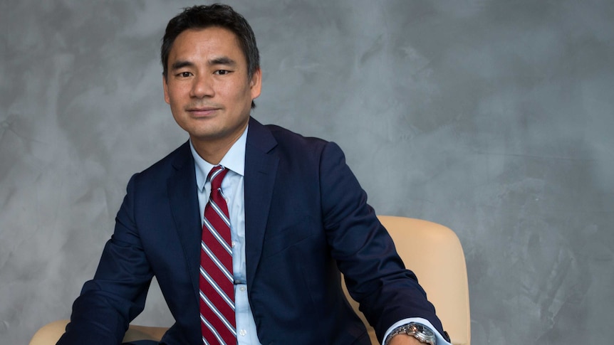 Westpac executive Yung Ngo sits on a chair with a grey background.