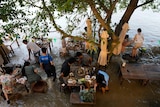 Diners sit among a flooded outdoor restaurant