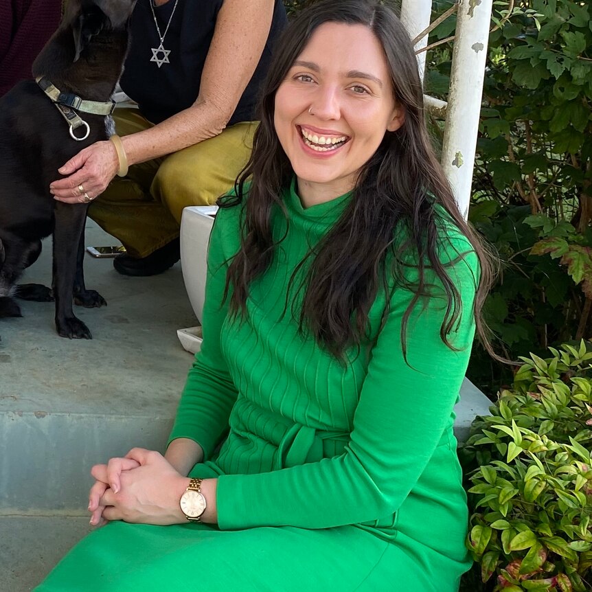 A lady in a green dress smiling and sitting down