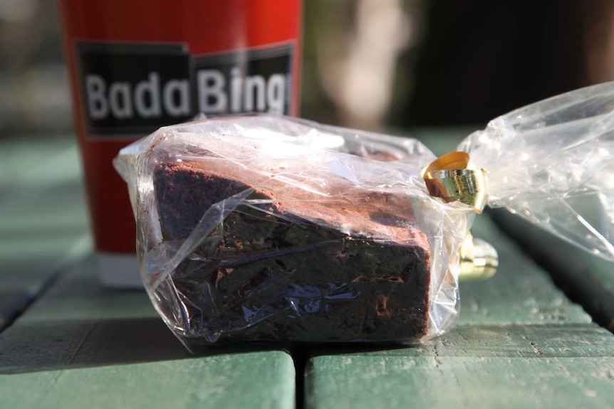 A chocolate brownie and takeaway coffee from Bada Bing, on a picnic table.