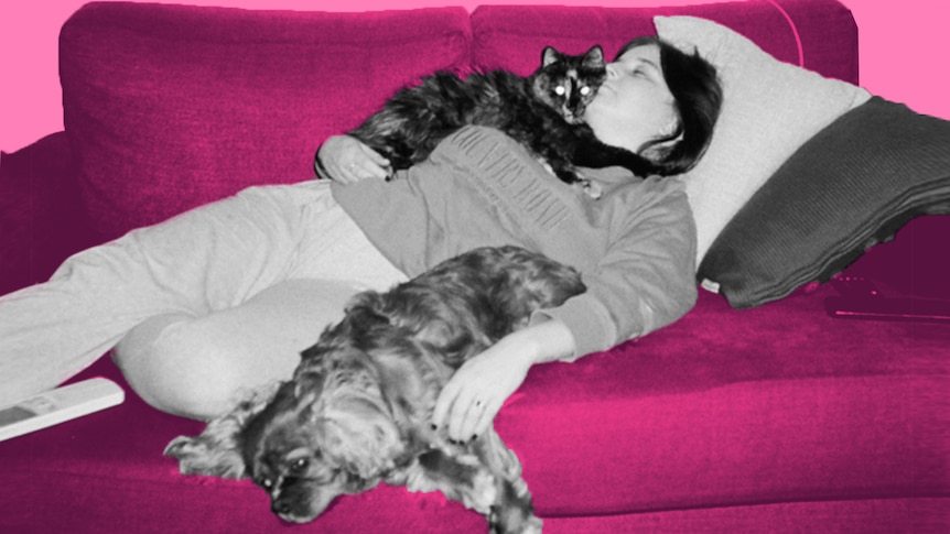 Georgia Brown lays on the couch with her cat and dog