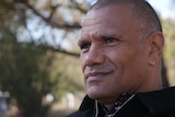 Portrait of Wesley Ford, relaxed against a blurred background of green eucalyptus trees.