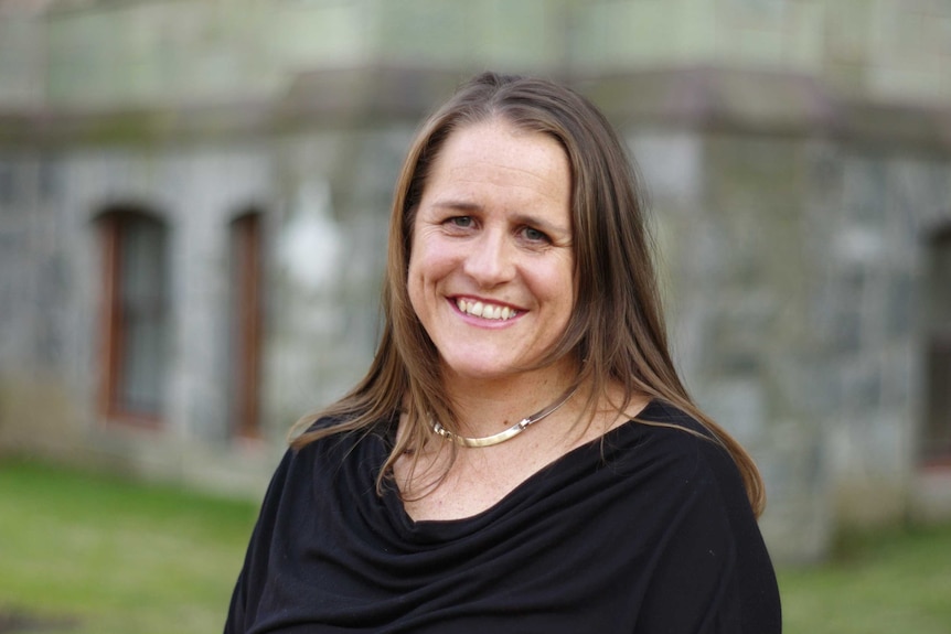 Claire Wardle smiles as she stands in front of a stone building.