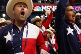 Texans in American-themed clothing yell on the floor of the Republican National Convention.