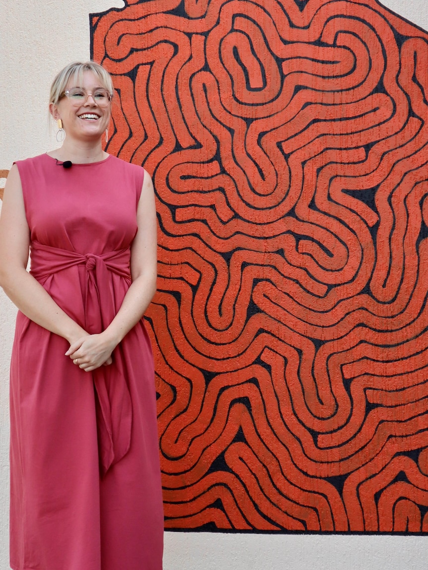 Susie Alderman stands in front of an artwork.