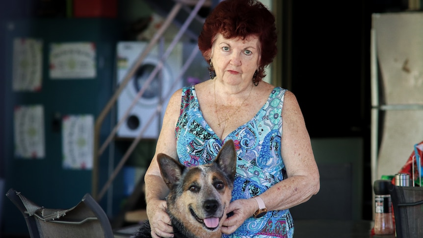 A woman and her dog in a garage, standing up and looking at the camera.
