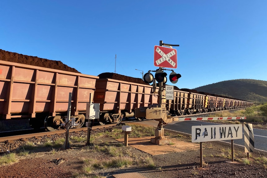 A Rio Tinto iron ore train, stretching for up to 3 kilometres, passes through a level crossing.