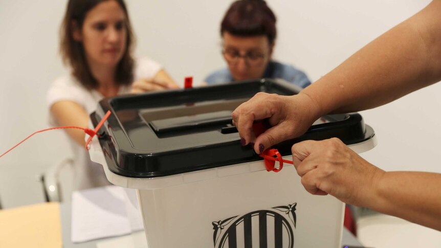 Voting officials seal a ballot box at a polling station in Spain