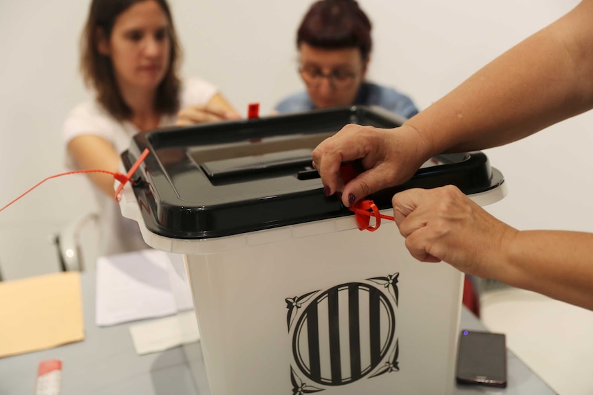 Voting officials seal a ballot box at a polling station in Spain