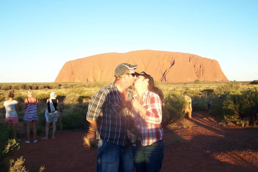 Jennie and Ray kiss in front of Uluru.
