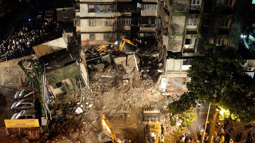 Excavators clear debris as rescue workers look for trapped people after a residential building collapsed in Mumbai.