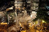 Excavators clear debris as rescue workers look for trapped people after a residential building collapsed in Mumbai.