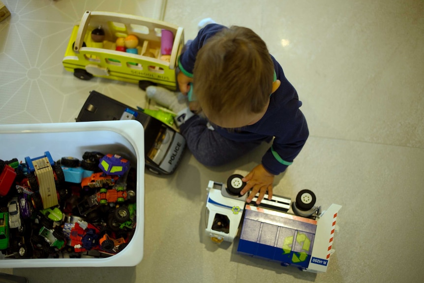 The top of a child's head who's sitting on floor playing with toyss