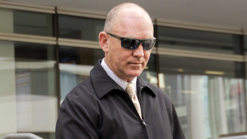 A balding man wearing dark sunglasses