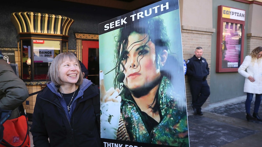 A woman stands with a sign outside of the premiere of the 'Leaving Neverland' Michael Jackson documentary.