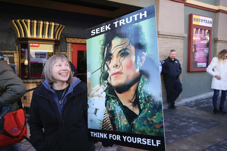 A woman stands with a sign outside of the premiere of the 'Leaving Neverland' Michael Jackson documentary.