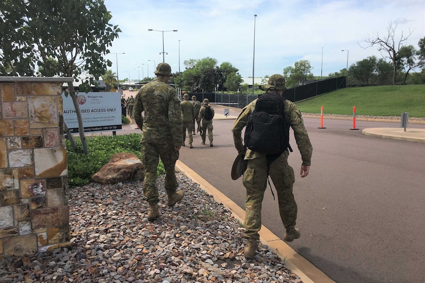 Defence force servicemen and trucks filled with gear arriving at the former Inpex workers camp.