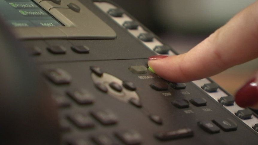 A woman's finger presses a button on a telephone