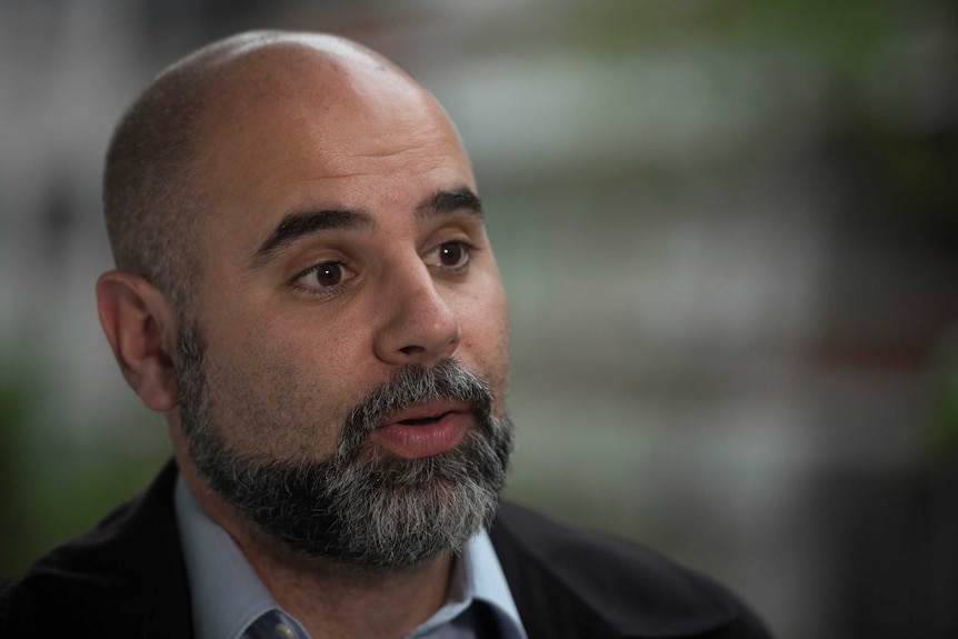 Maximiliano Ruiz, a bald man with a greying beard, speaks during an interview.