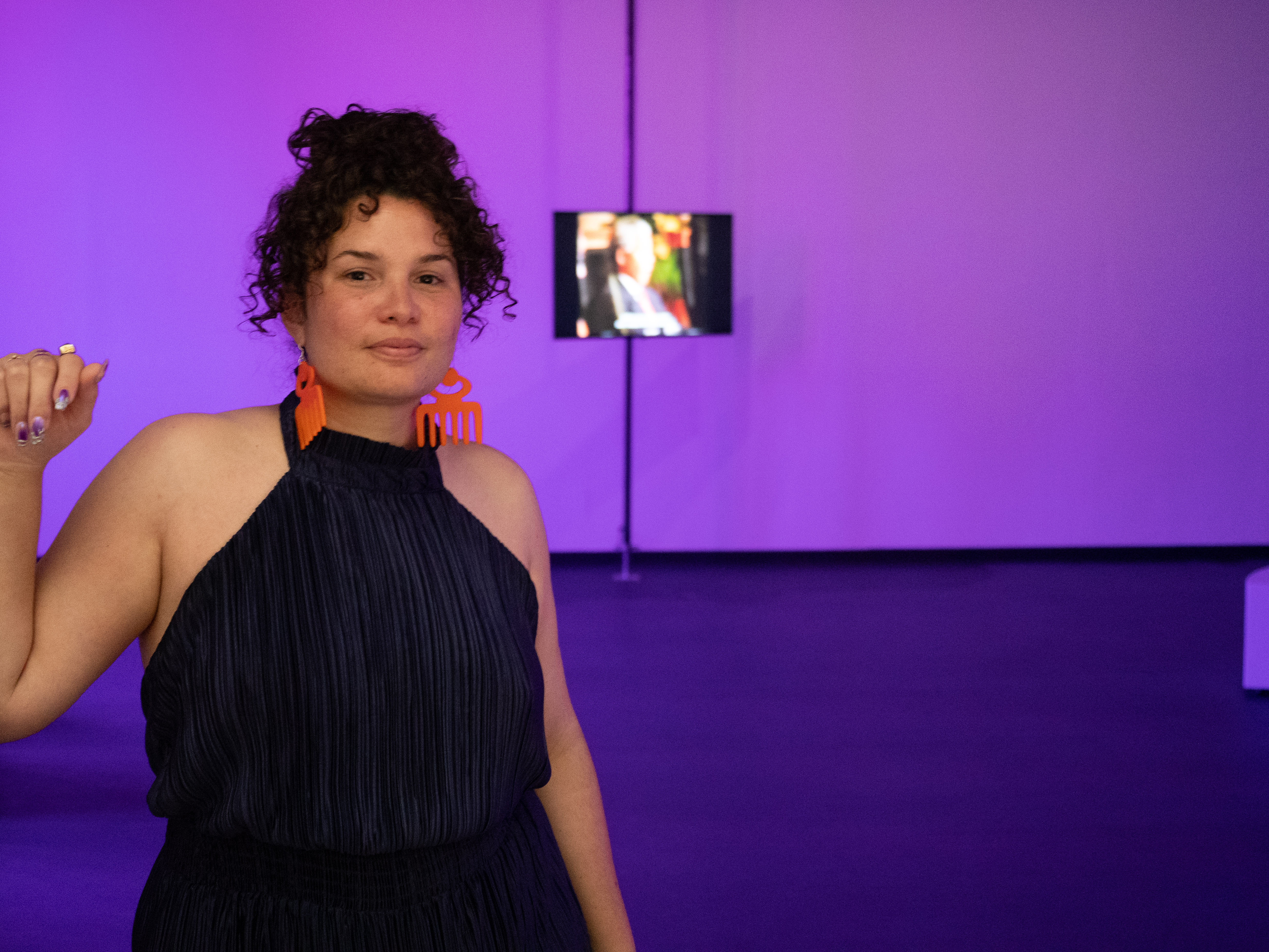 Roberta Joy Rich in her exhibition The Purple Shall Govern with TV screen in background